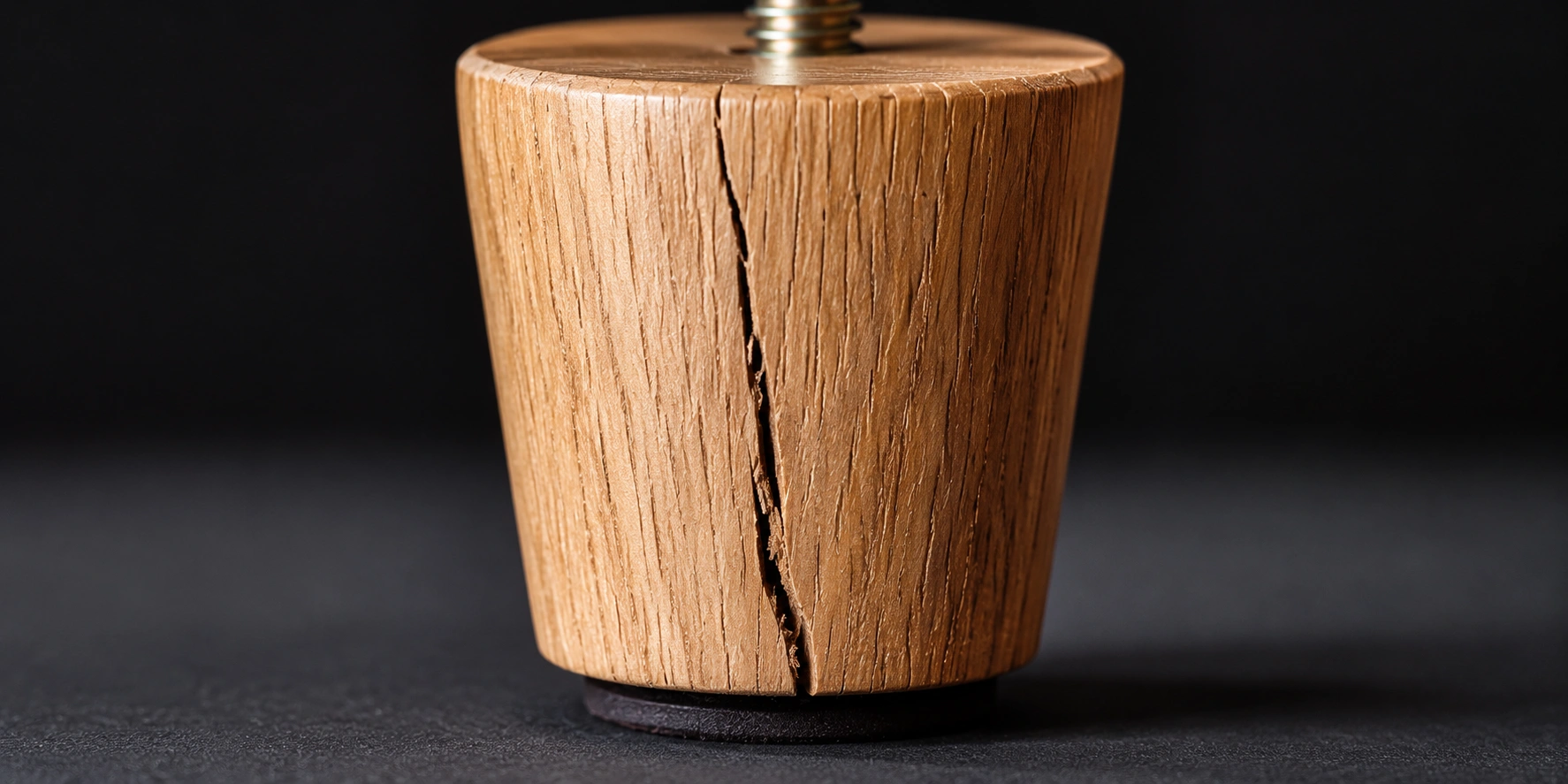 Close-up of a cracked wooden sofa leg showing damage that requires replacement