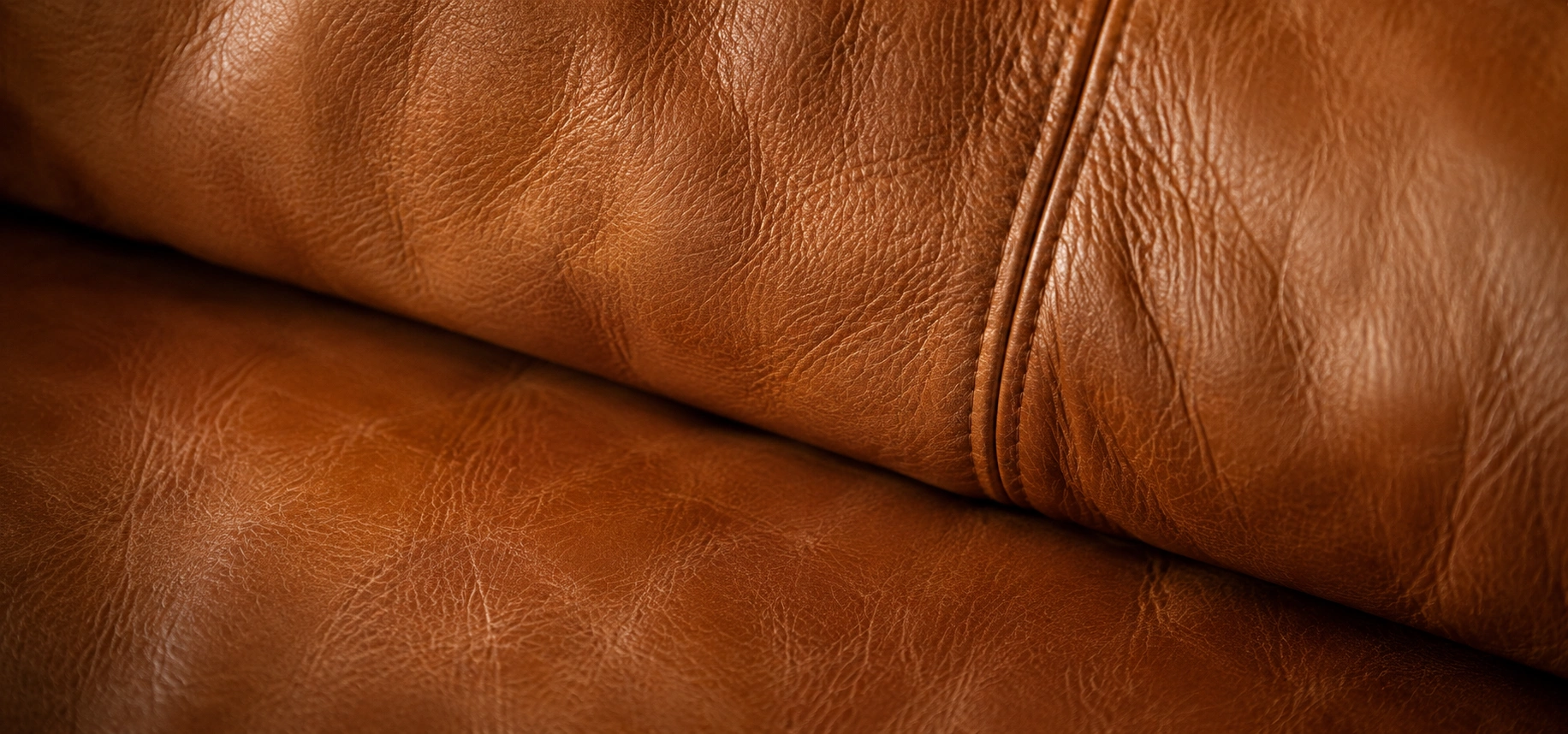 Close-up texture of full-grain leather sofa upholstery showing natural grain