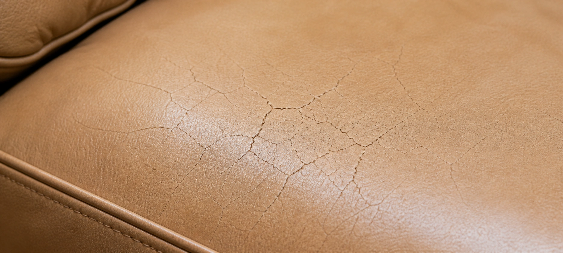 Surface cracks on leather sofa seat cushion caused by dryness and loss of flexibility