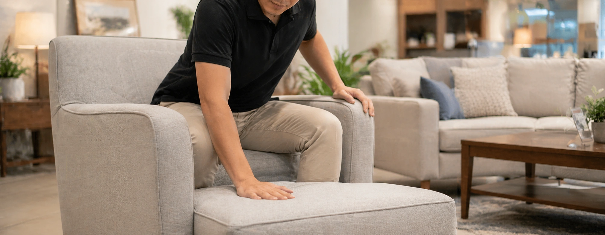 Person sitting in a sofa chair testing seat cushion firmness and back support