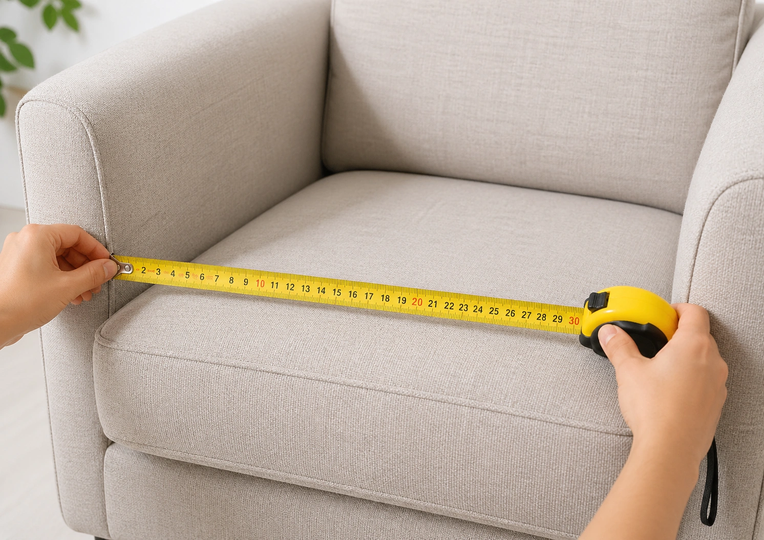 Person measuring sofa chair dimensions with a tape measure