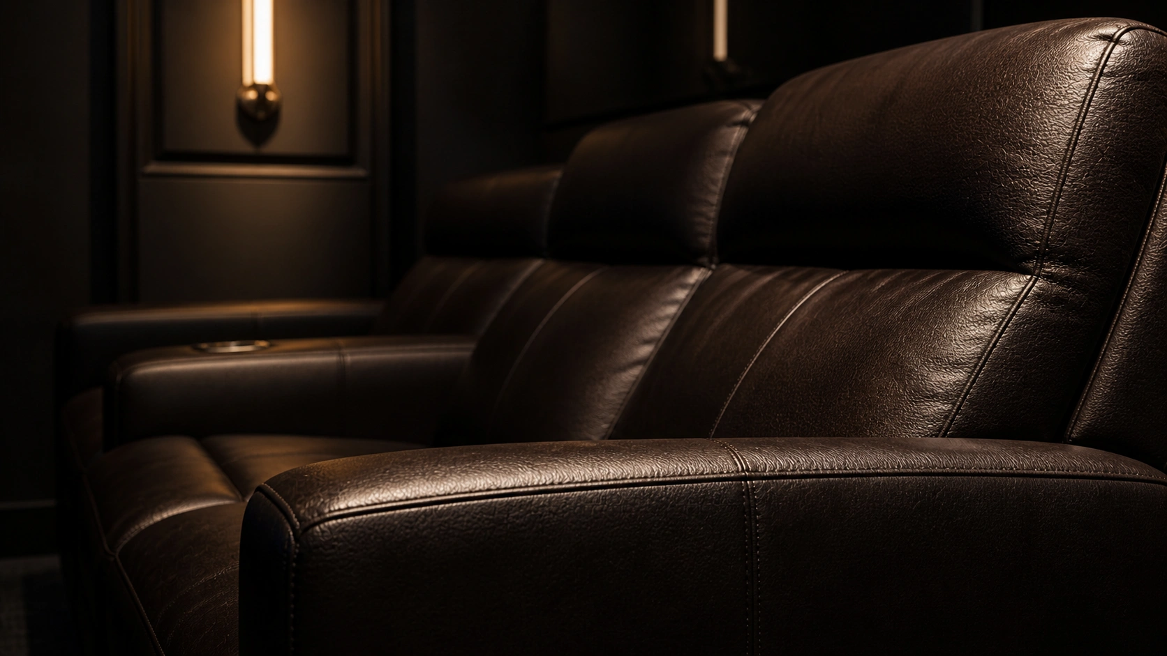 Dark leather home theater sofa showing premium texture and finish in a dimly lit room